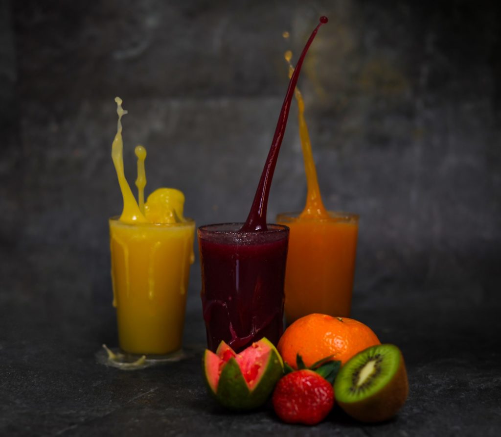 3 glasses of fruit/veggie juice on a black background