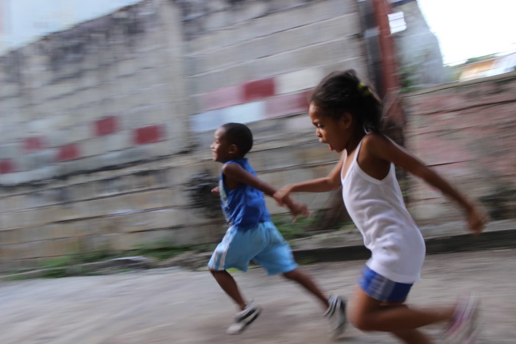 two young children happily running through neighborhood