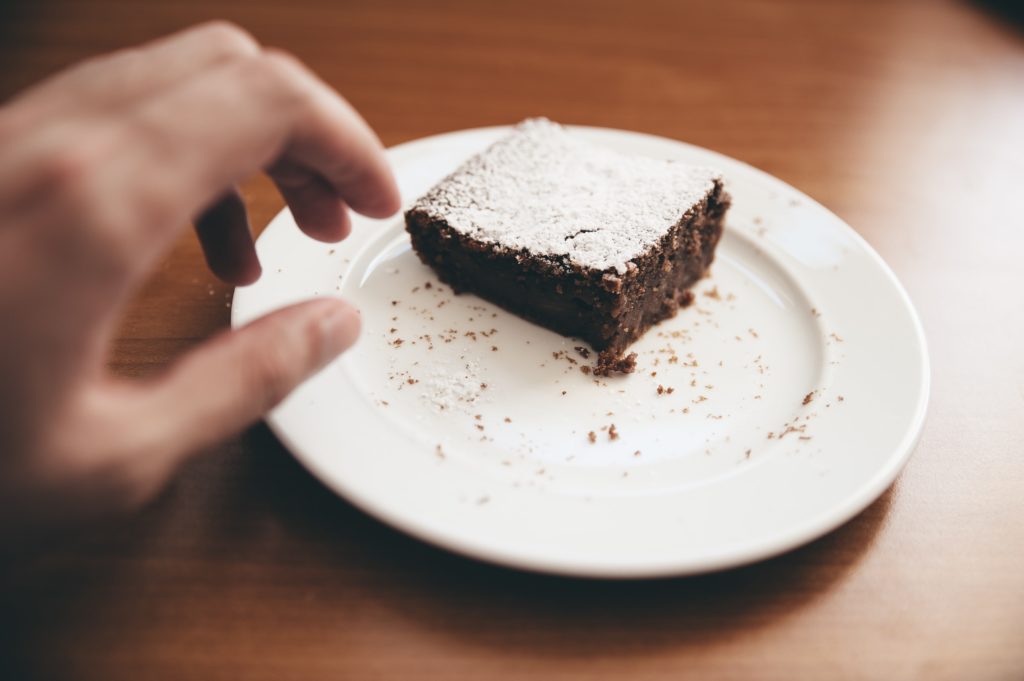 hand reaching for brownie on table