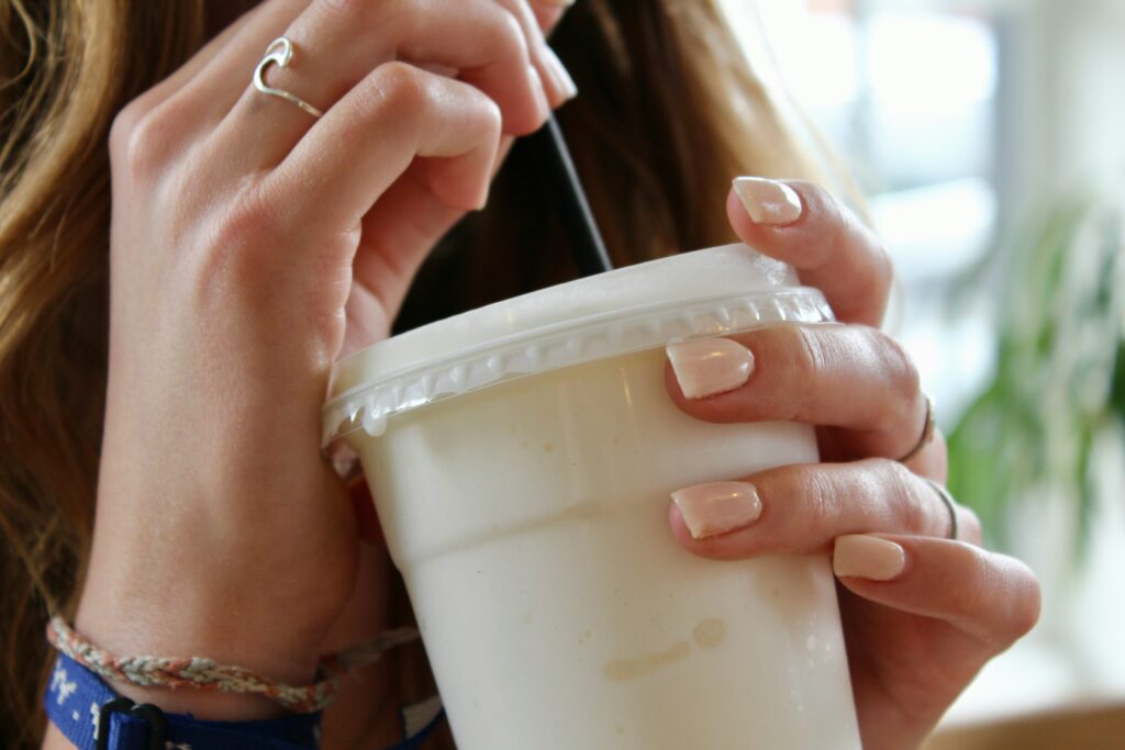 woman sipping smoothie out of straw with clear cup