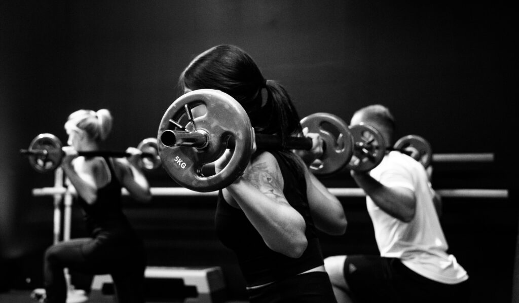 profile view of two women and one man lifting weights