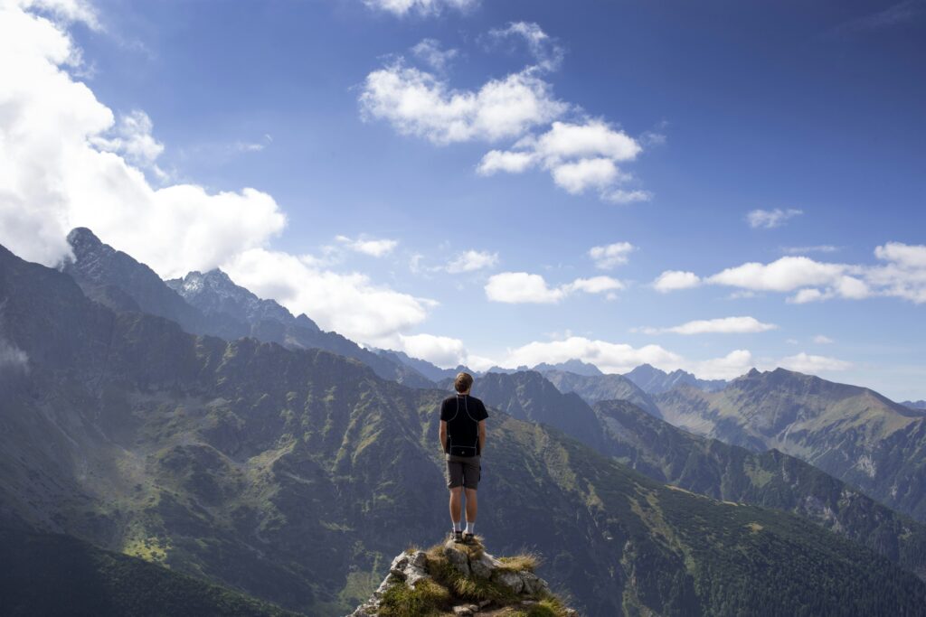 man standing on mountain peak, outside of his comfort zone